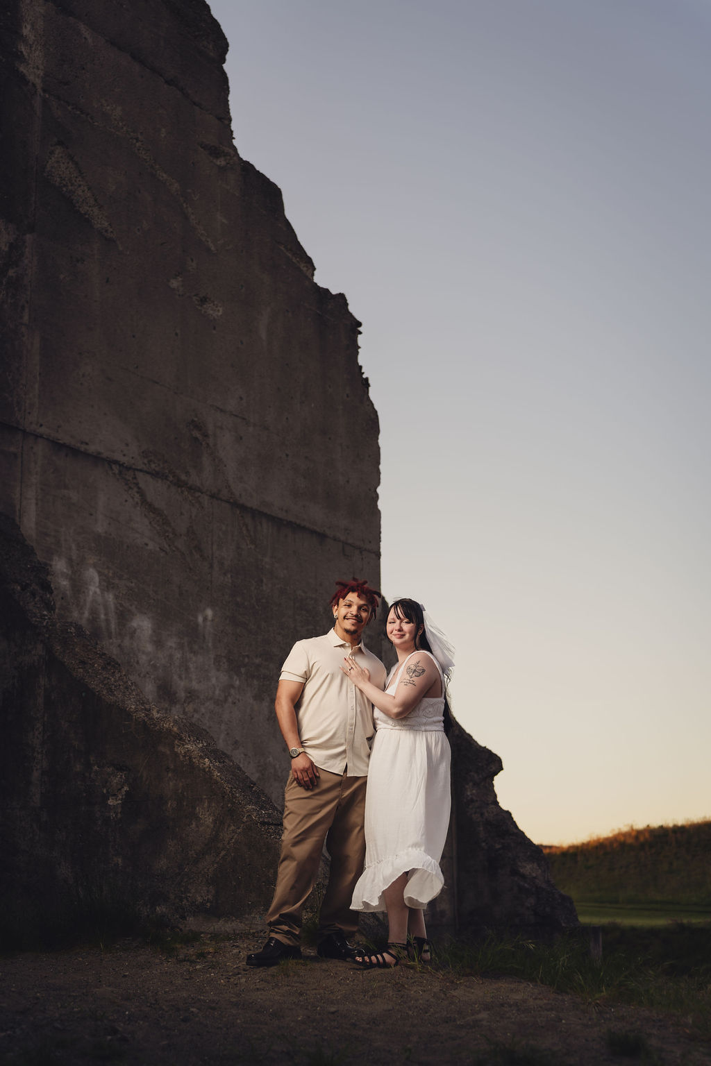 Engaged couple standing together at the base of the concrete ruins at Chambers Bay near Tacoma at dusk