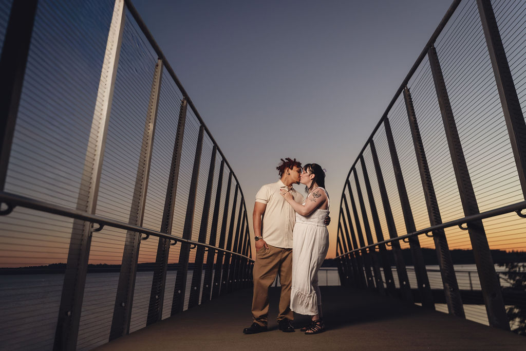 Engaged couple sharing a kiss on the boardwalk pier at sunset at Chambers Bay near Tacoma