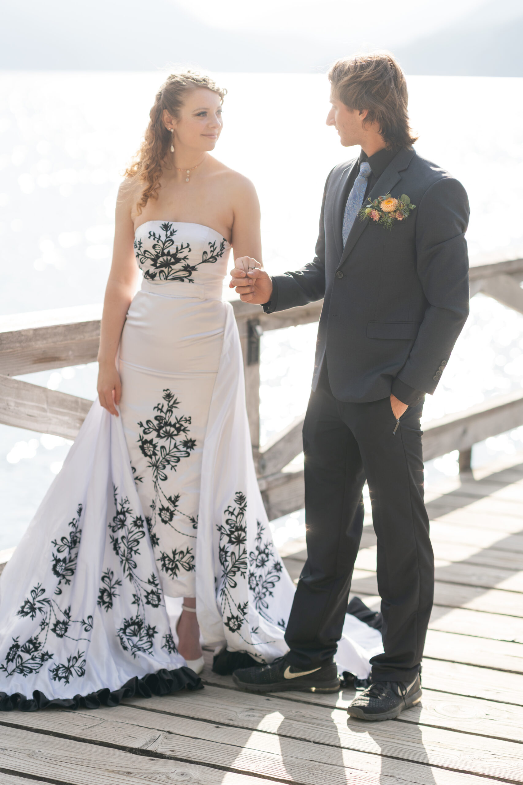 Kitsap County wedding photographer photo of a bride and groom holding hands on a sunlit lakeside dock