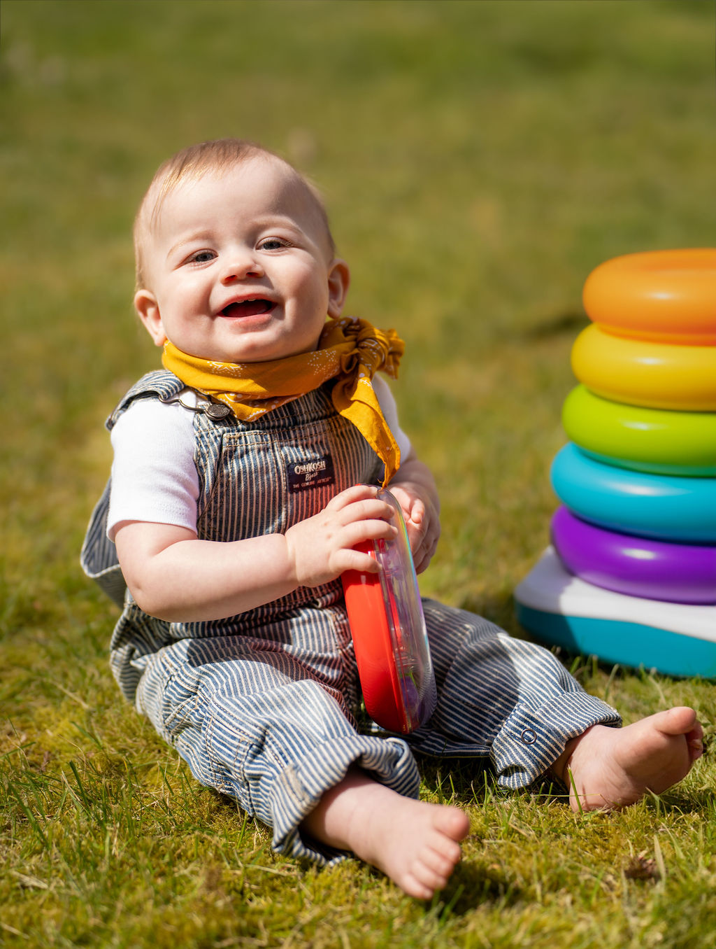 Baby sitting in the grass with a stacking toy during an outdoor family photo session in Kitsap County, Washington
