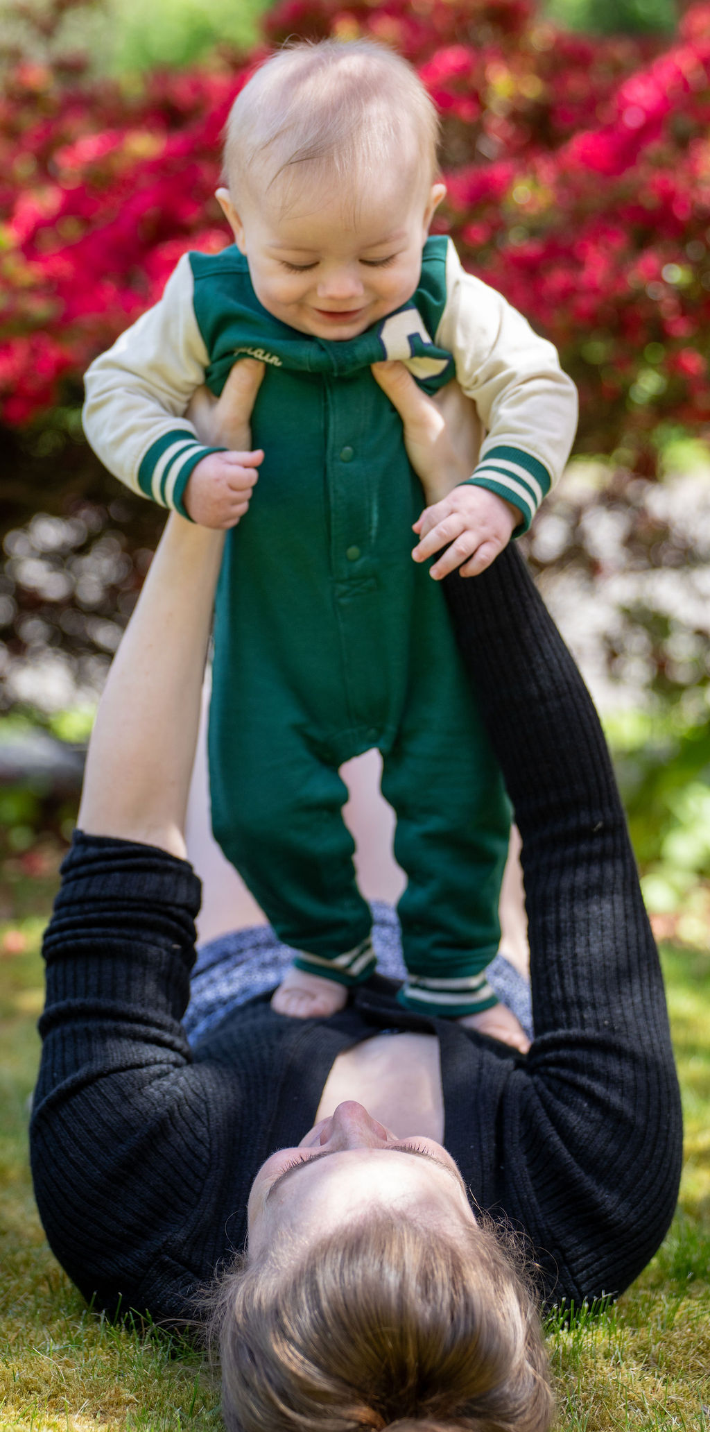 Mother lying in the grass lifting her baby during an outdoor family session in Kitsap County