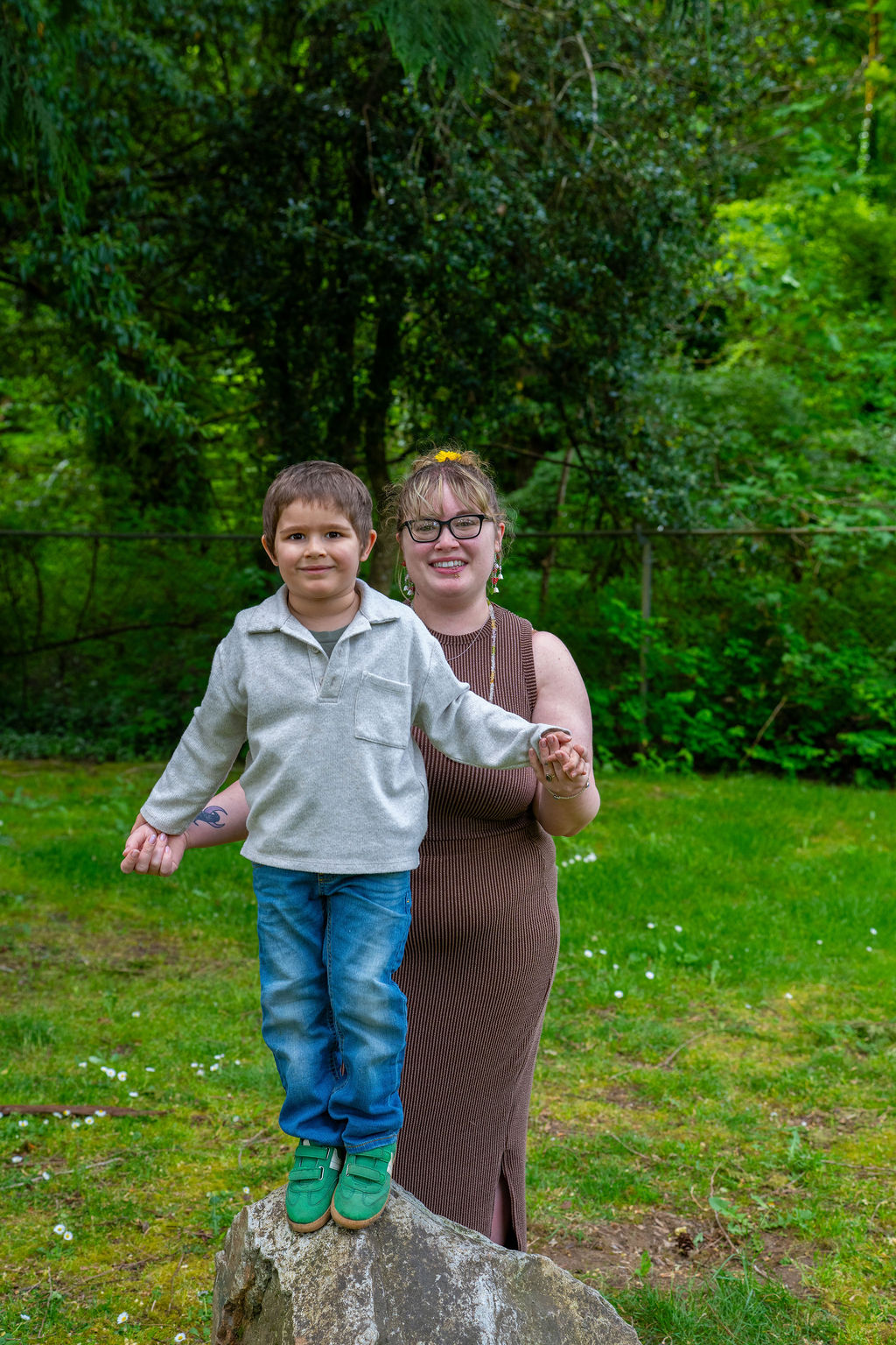 Young boy balancing on a rock while holding his mother's hand at a Kitsap County park