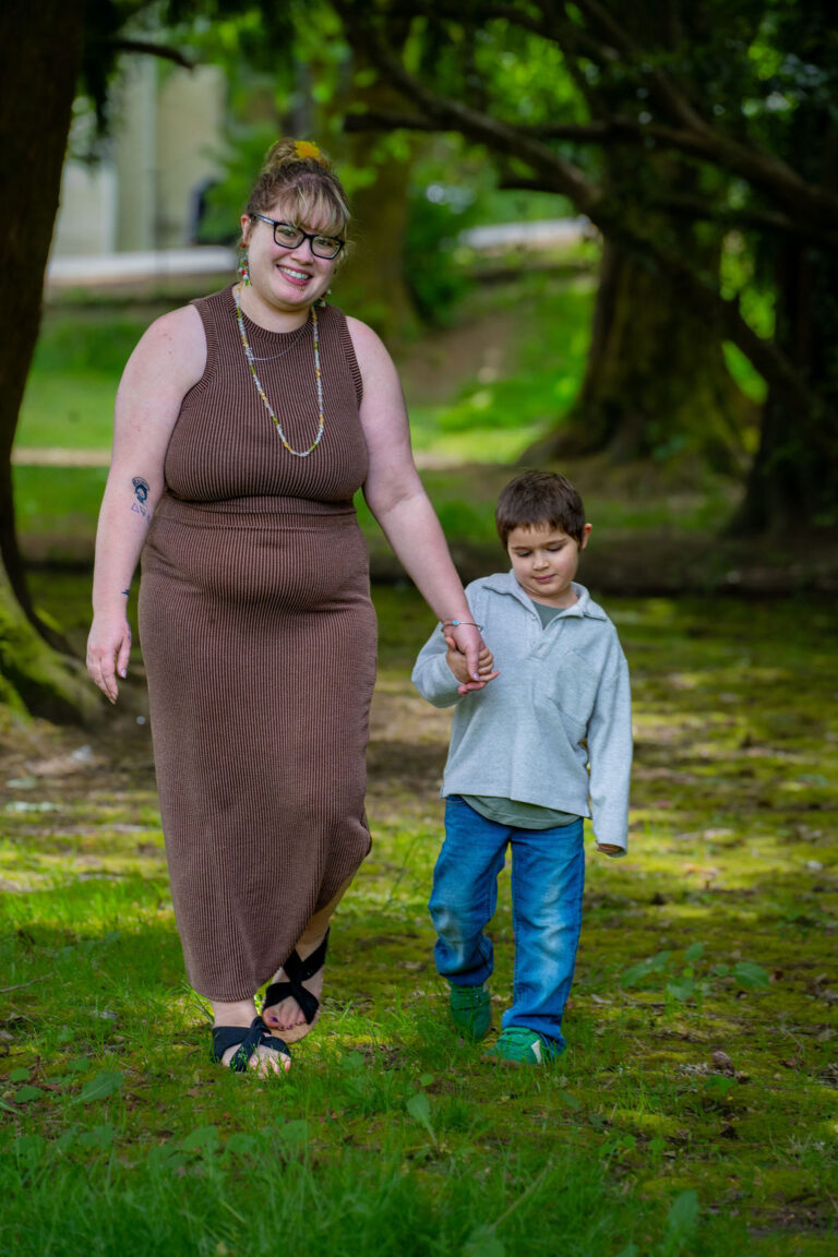 Mother and son walking hand in hand under the trees at a Kitsap County park. family photos park Kitsap County