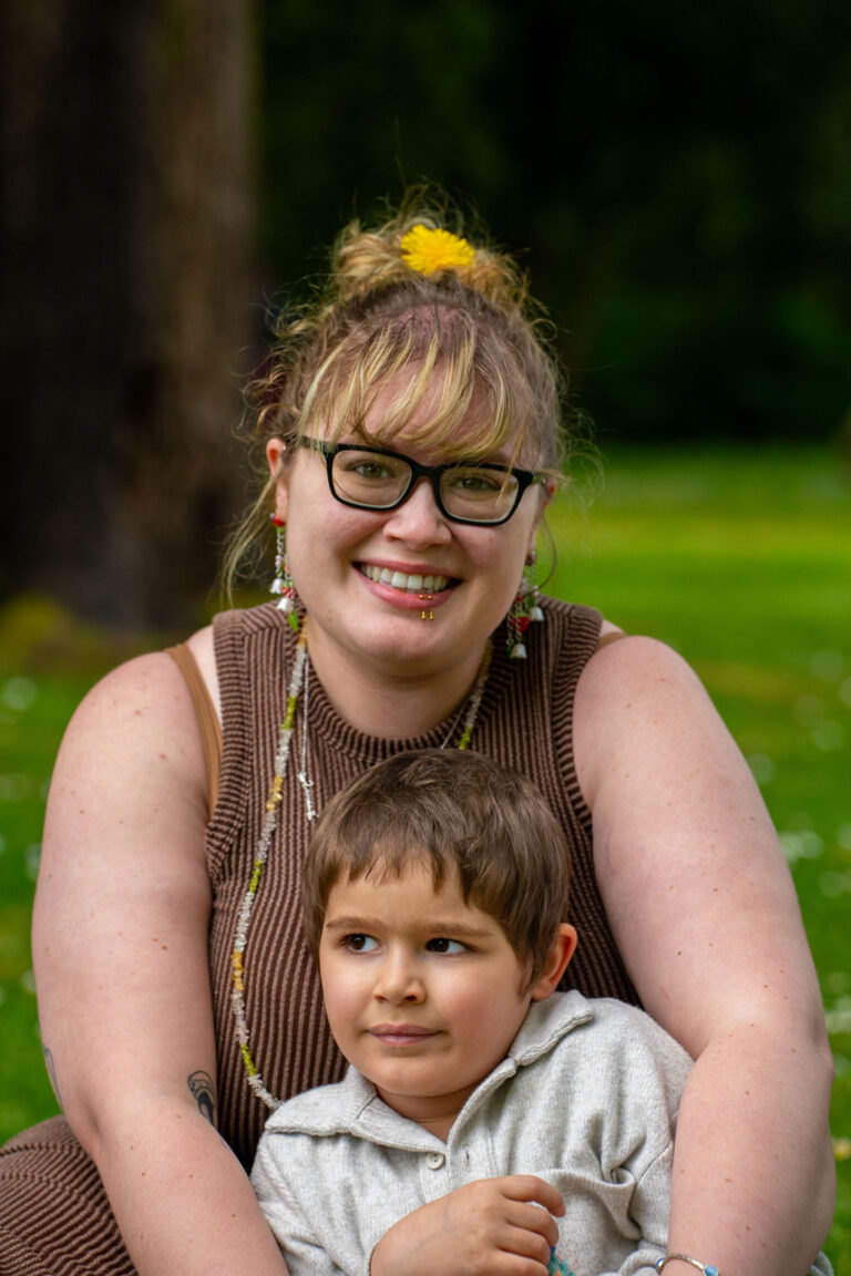 Mother embracing her young son from behind in a green Kitsap County park