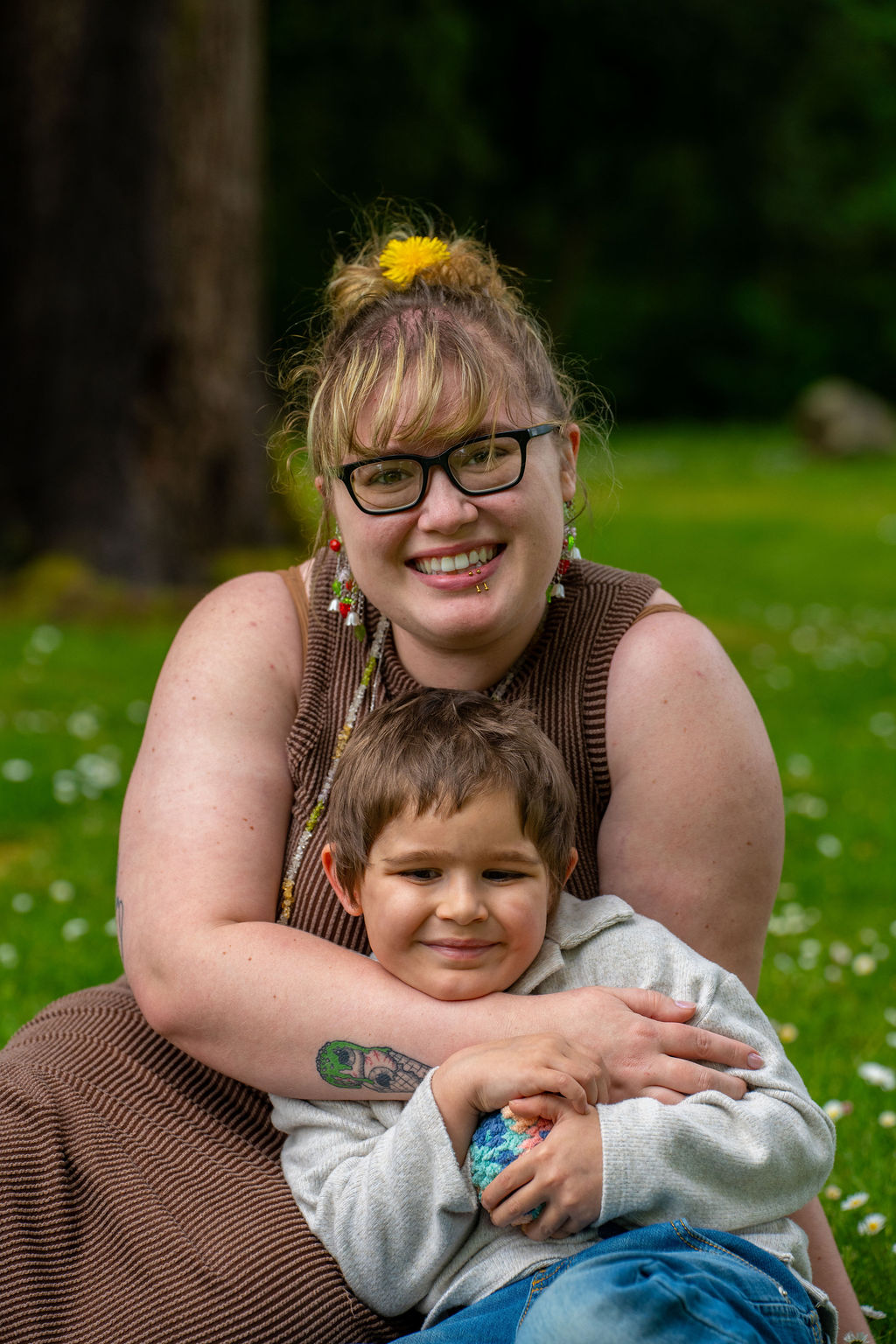 Mother embracing her young son from behind in a green Kitsap County park