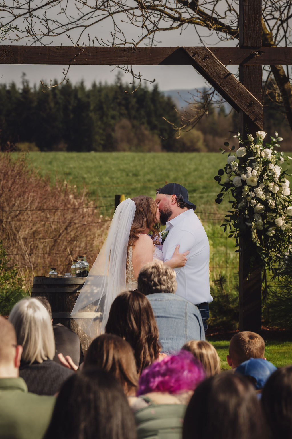 Bride and groom first kiss during their Mason Jar Gathering Barn wedding ceremony