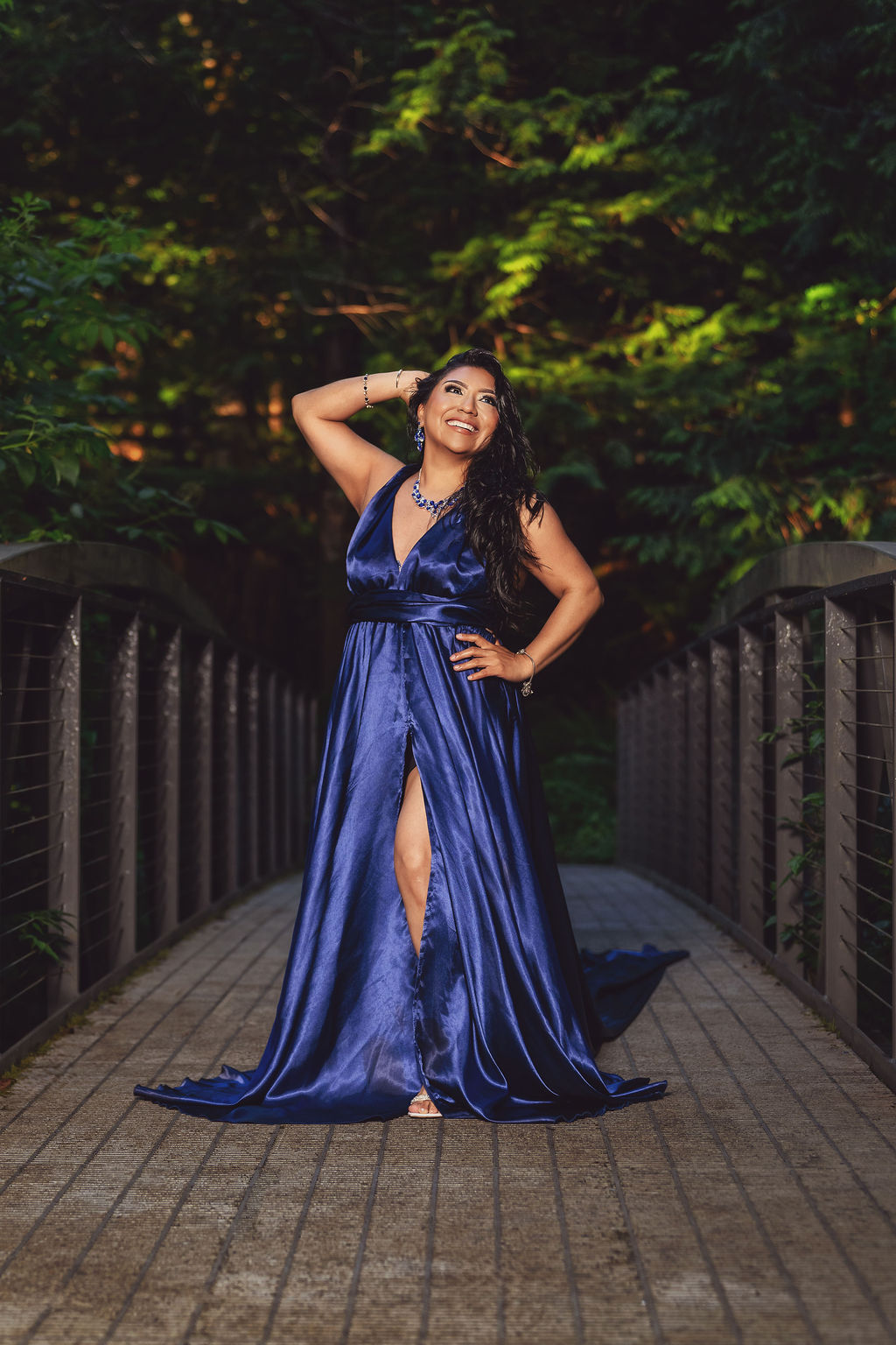 Woman in a royal blue gown posing on a wooden footbridge surrounded by greenery at Scenic Beach State Park near Seabeck
