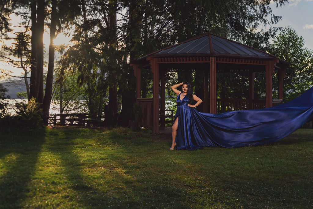 Woman in a royal blue gown with a long flowing train posing on the lawn by the gazebo at Scenic Beach State Park near Seabeck at sunset
