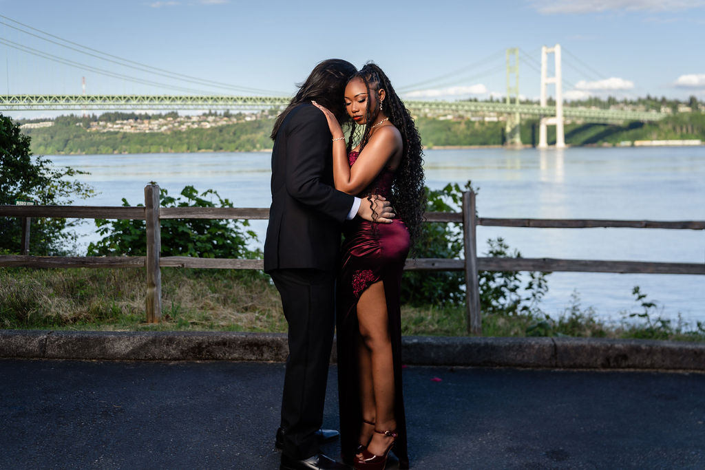 Prom couple holding each other forehead to forehead in front of the Tacoma Narrows Bridge near South Kitsap