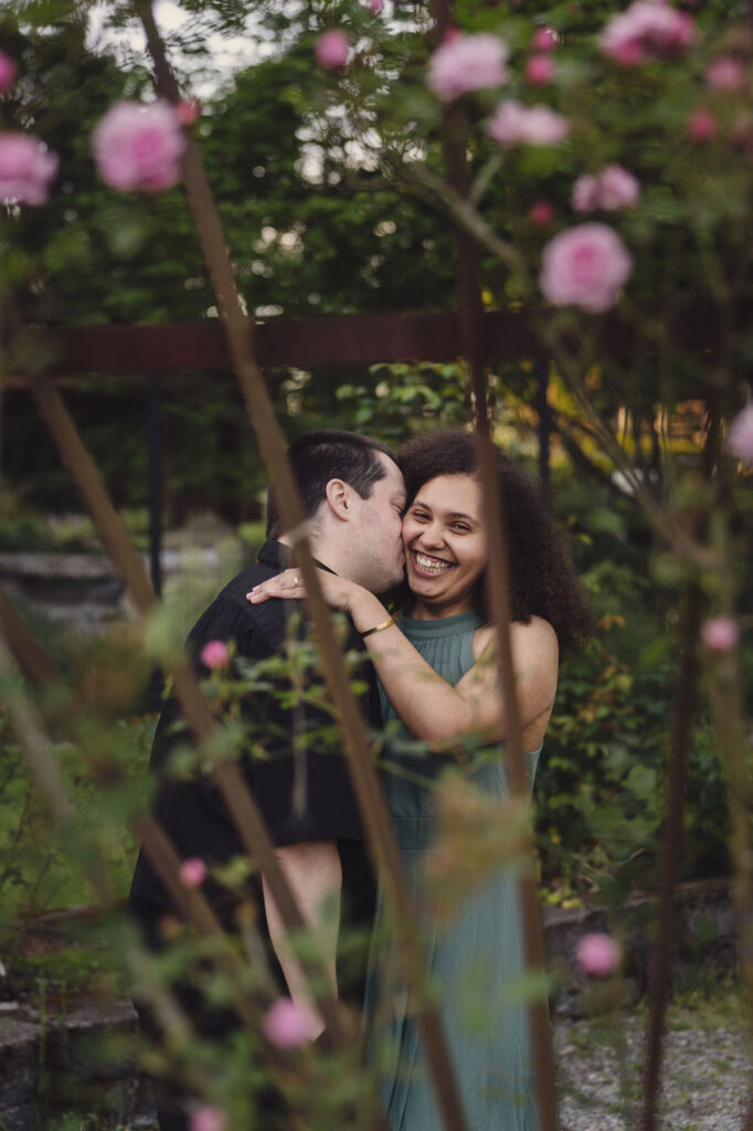 RJ and Maya sharing a romantic moment surrounded by roses at Point Defiance Rose Garden in Tacoma