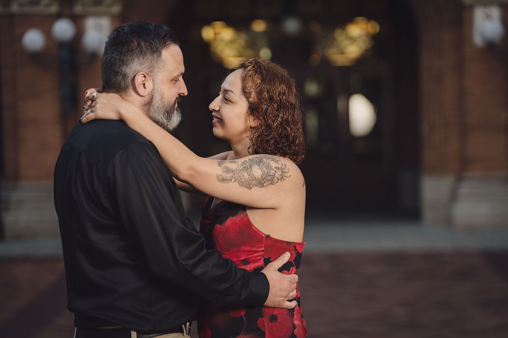 Engaged couple sharing a tender embrace in front of the carved entrance of Stadium High School in Tacoma at golden hour