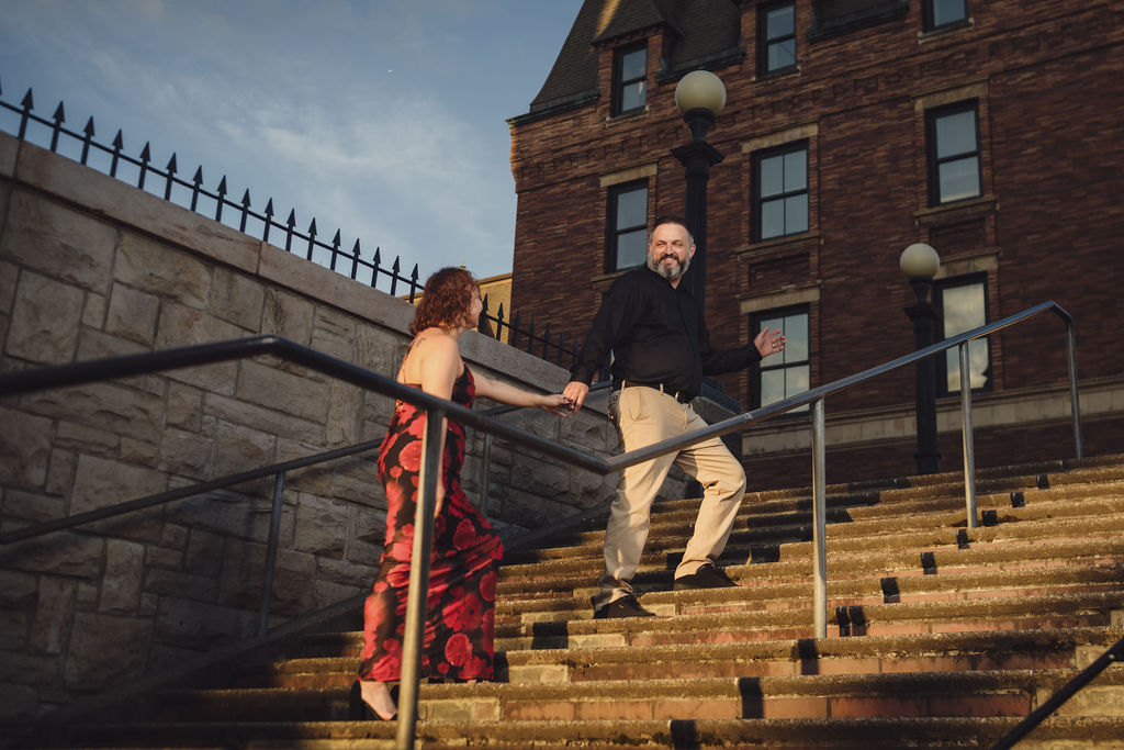 Engaged couple sharing a playful moment on the grand exterior staircase of Stadium High School in Tacoma at golden hour