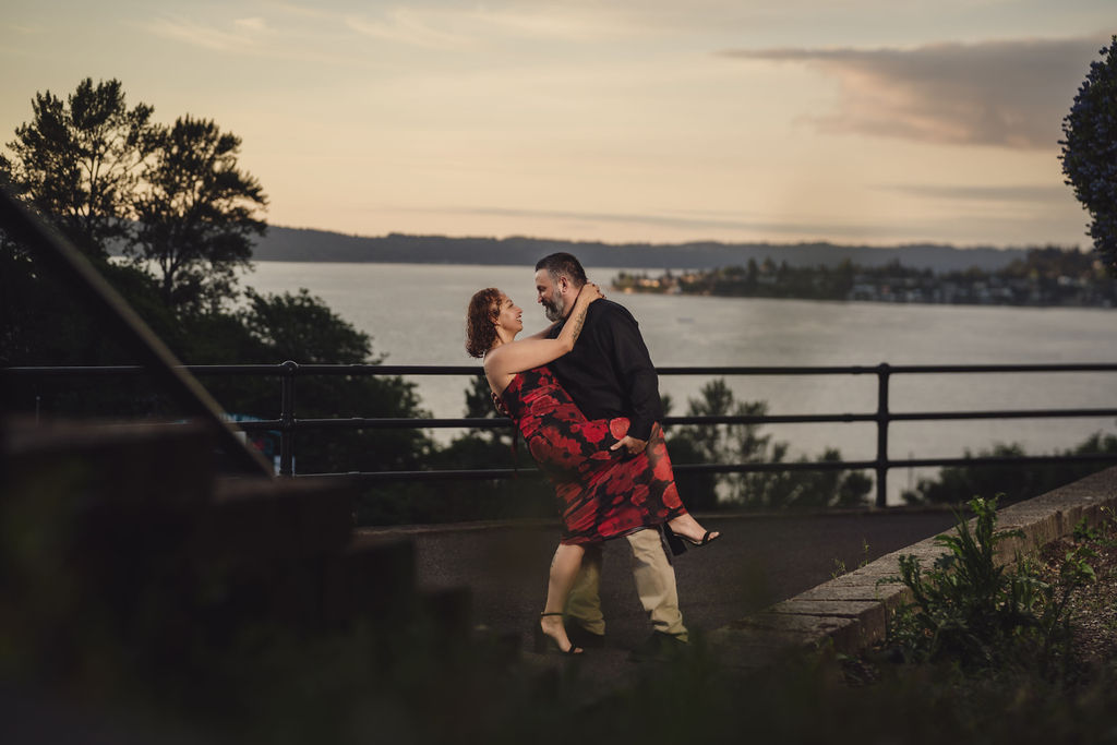 Partner dipping his fiancee at the Stadium Bowl overlook with Commencement Bay behind them in Tacoma at sunset