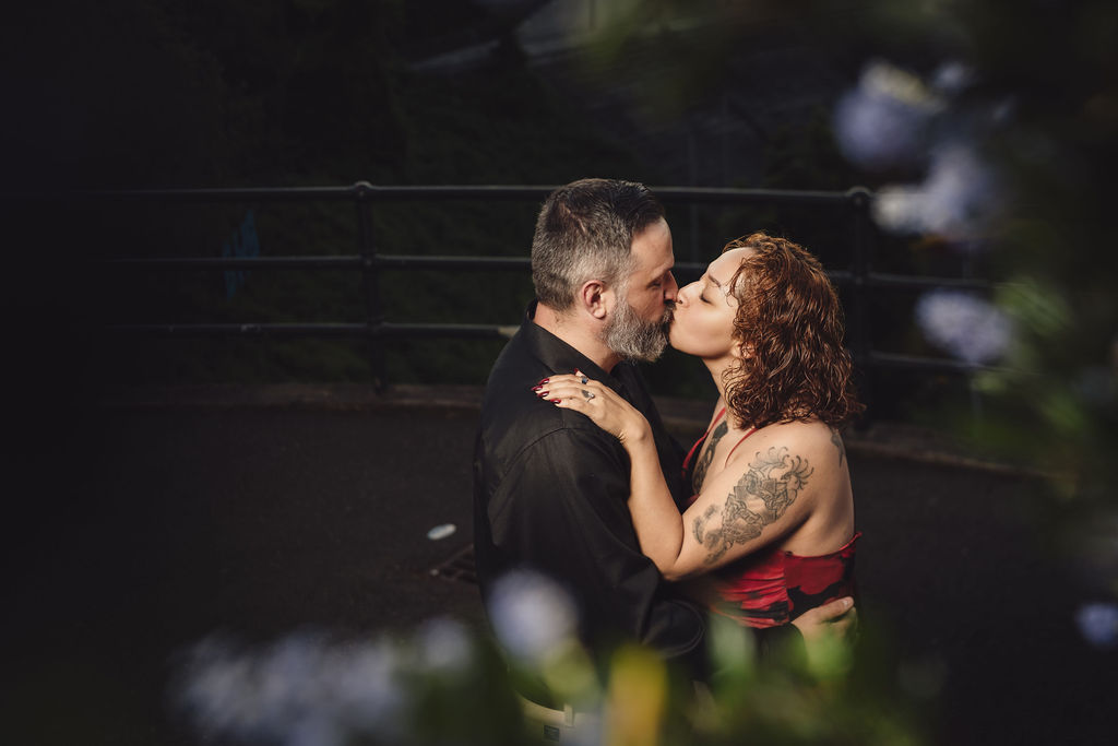 Engaged couple kissing framed by spring blossoms at the Stadium Bowl overlook in Tacoma