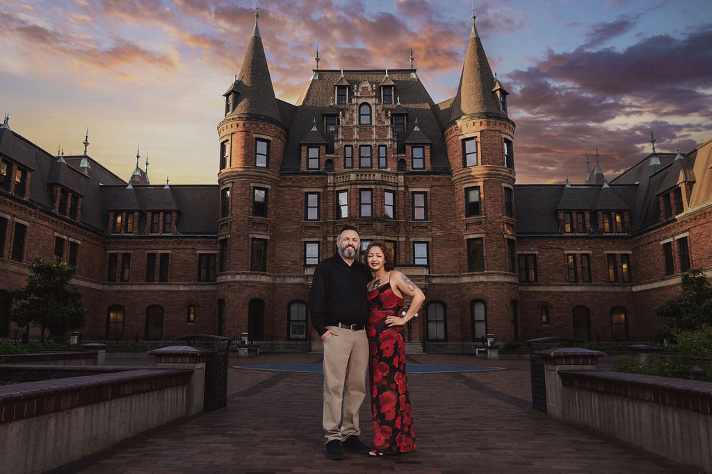 Engaged couple in front of Stadium High School in Tacoma under a colorful sunset sky, dramatic and romantic Tacoma engagement photography