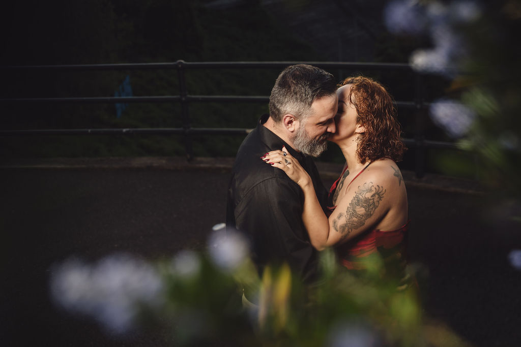 Engaged couple resting forehead to forehead framed by purple blossoms during their Tacoma engagement session