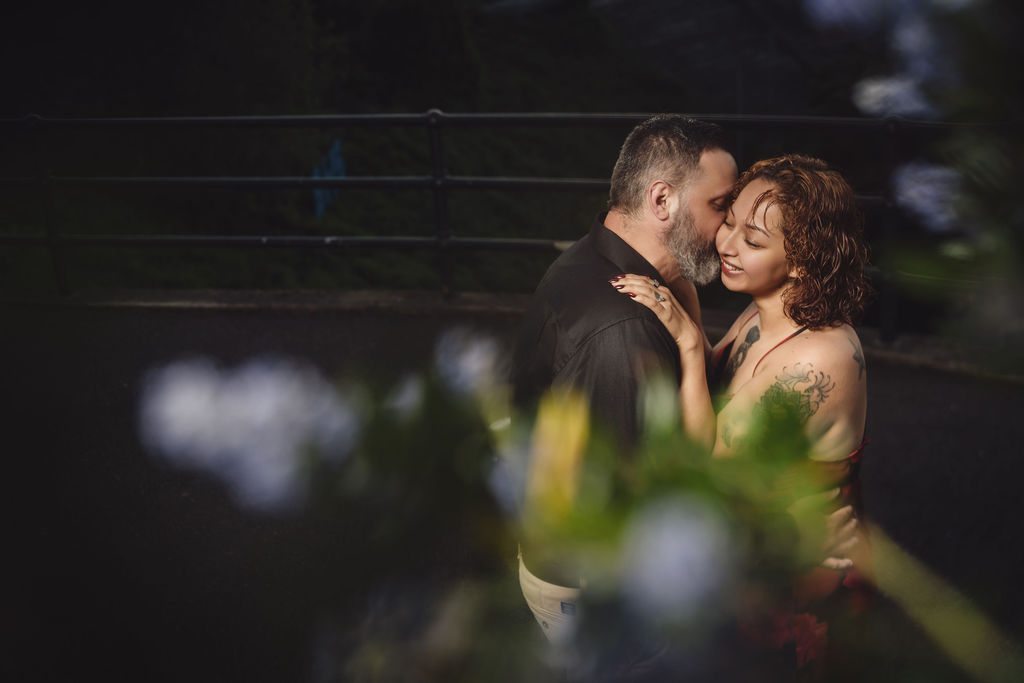 Engaged couple smiling forehead to forehead framed by purple blossoms during their Tacoma engagement session