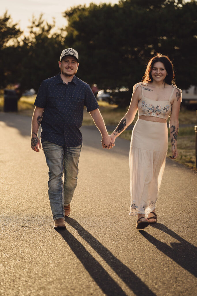 Engaged couple walking hand in hand at golden hour at Chambers Bay near Tacoma