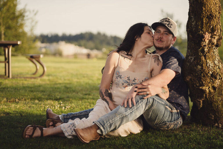 Engaged couple sharing a sweet moment in the grass at golden hour in Washington