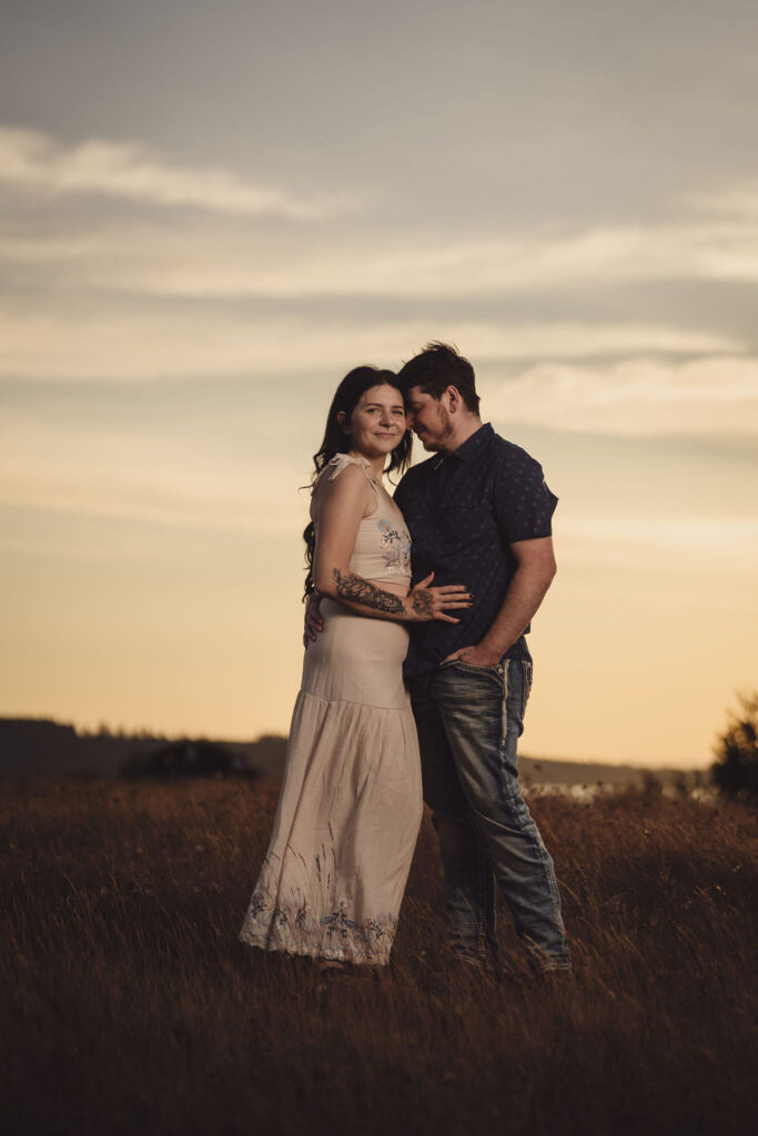 Engaged couple embracing in a golden field at sunset at Chambers Bay near Tacoma
