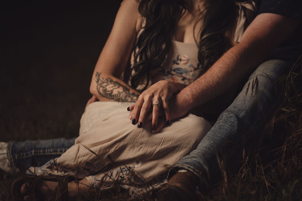 Close up of an engagement ring as a couple holds hands in the grass at Chambers Bay in University Place