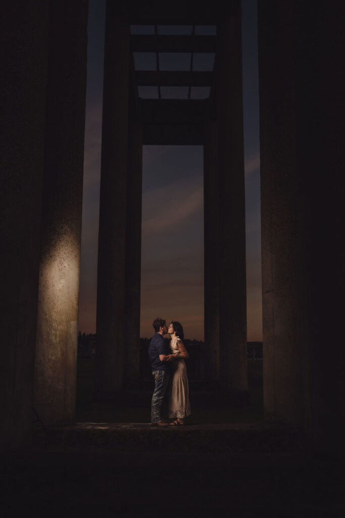 Engaged couple framed by a concrete archway of the Chambers Bay ruins at sunset near Tacoma