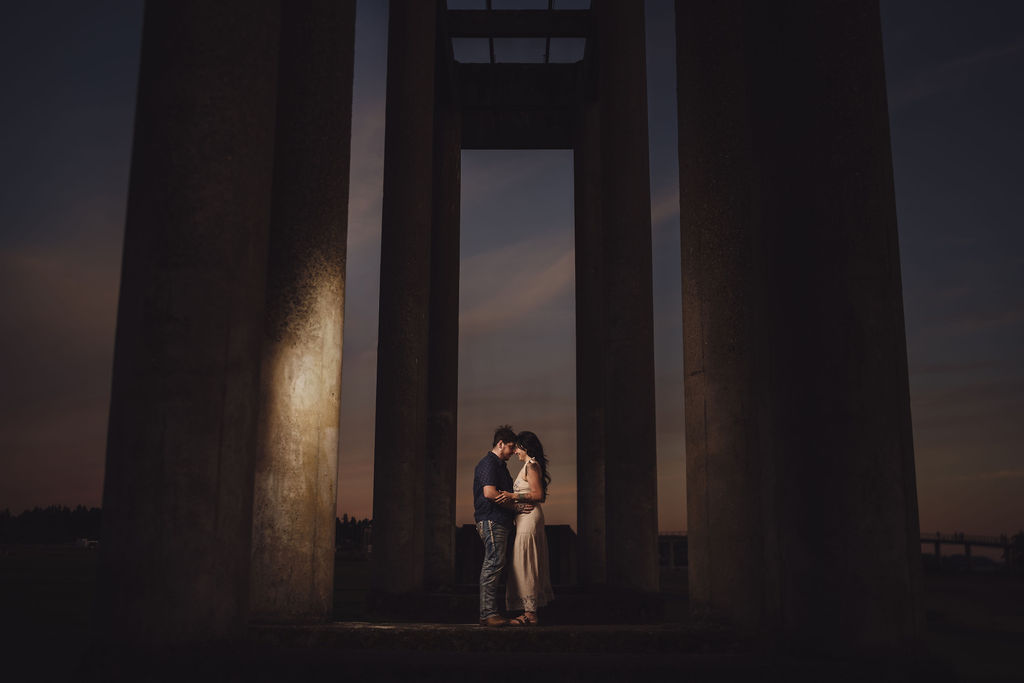 Partner dipping his fiancee beneath the concrete columns at Chambers Bay near Tacoma