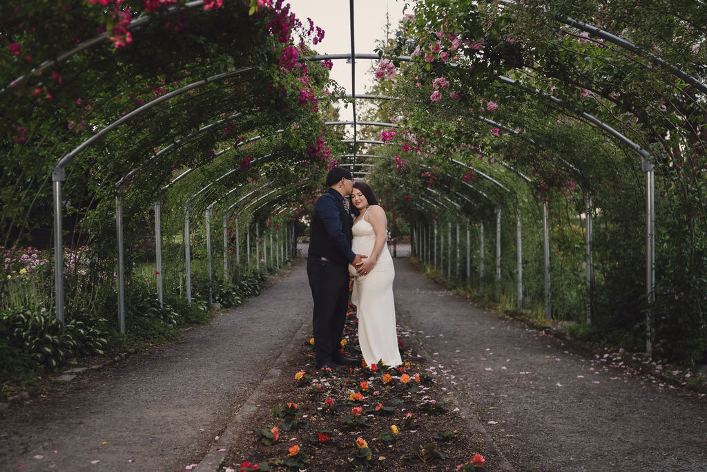 Couple in formal attire sharing a romantic moment at Point Defiance Rose Garden in Tacoma, engagement session by Nautical Moments Photography