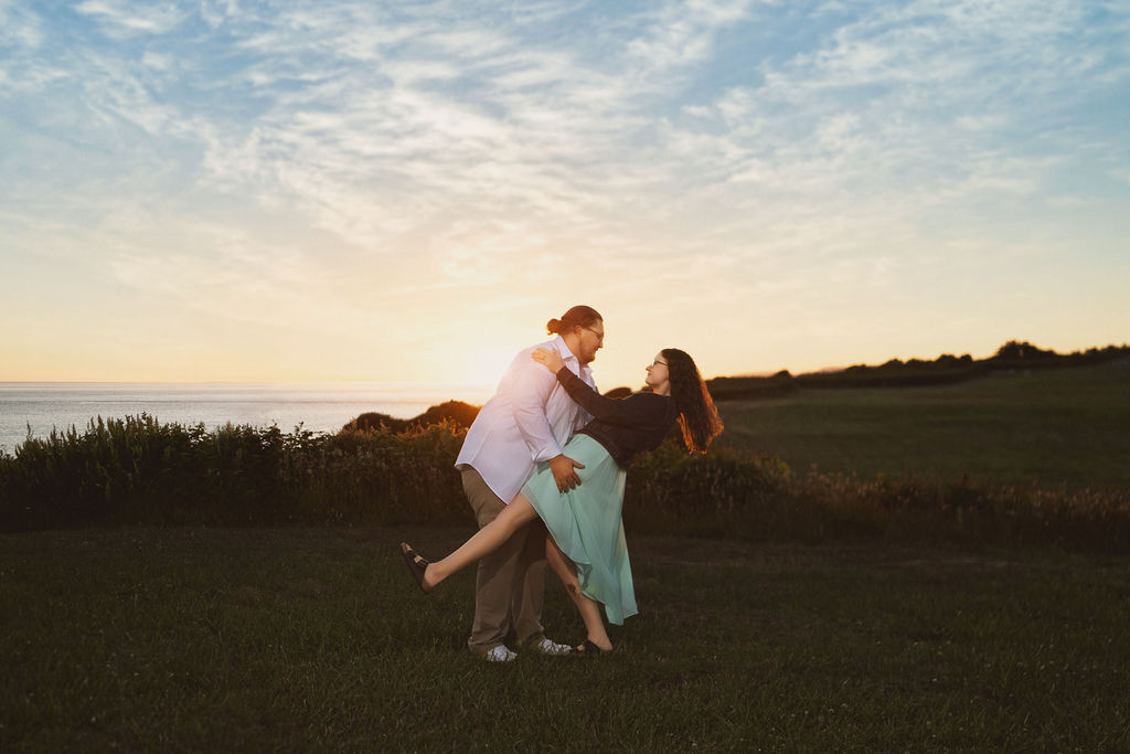 Partner dipping his fiancee in the grass under a big blue sky at Fort Casey State Park on Whidbey Island