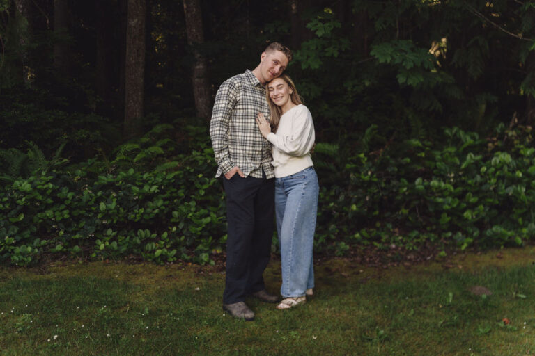 Engaged couple cuddling at the forest edge during their Seabeck engagement photos