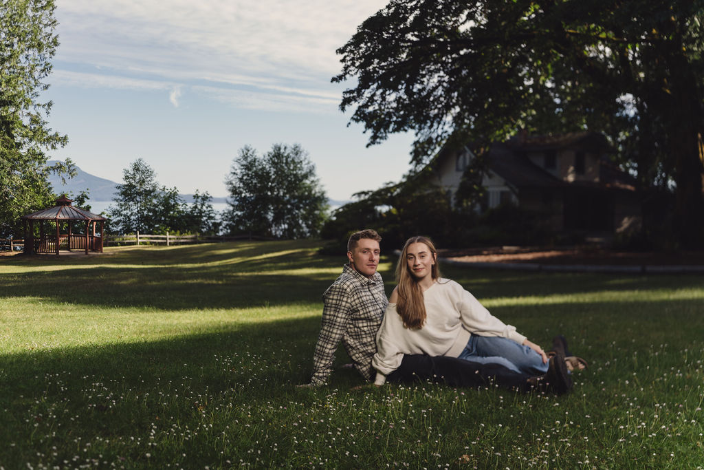 Engaged couple relaxing on the wide lawn at Scenic Beach State Park in Seabeck Washington
