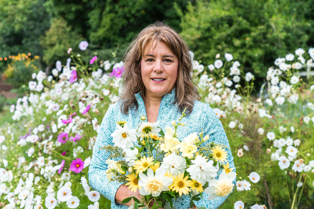 Florist holding a fresh bouquet among white cosmos at Vinnocki Flower Farm in Seabeck