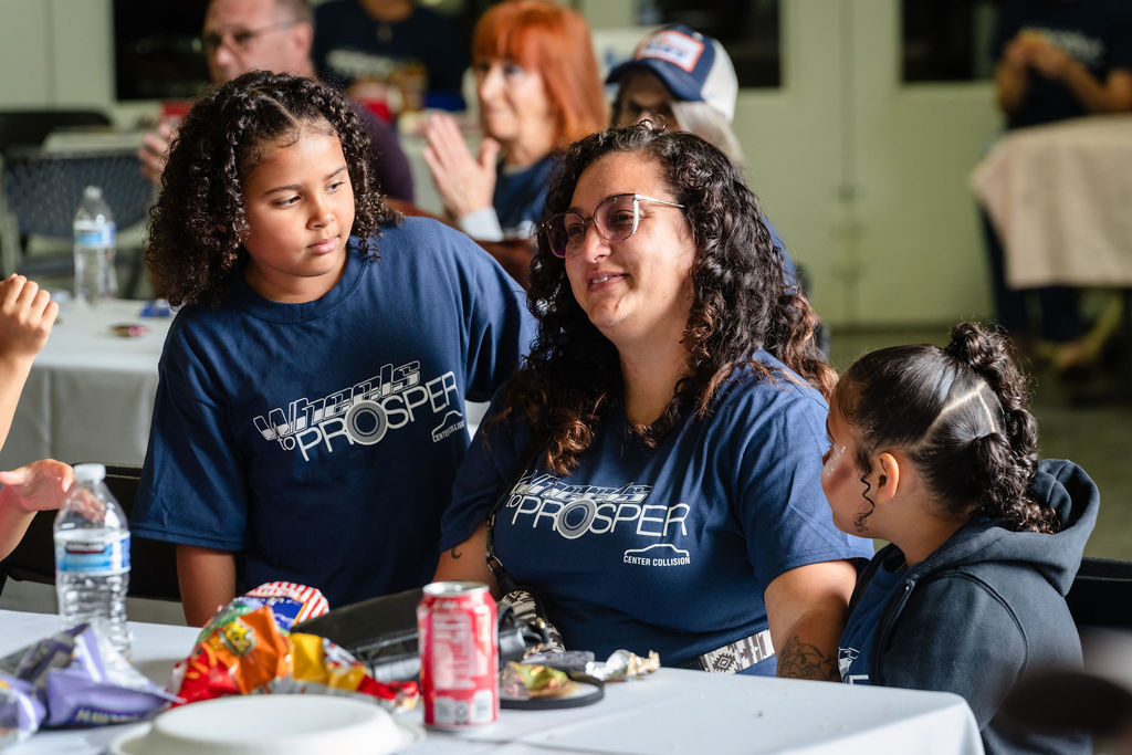 A mother and her daughters seated together with food at the Tacoma charity car giveaway