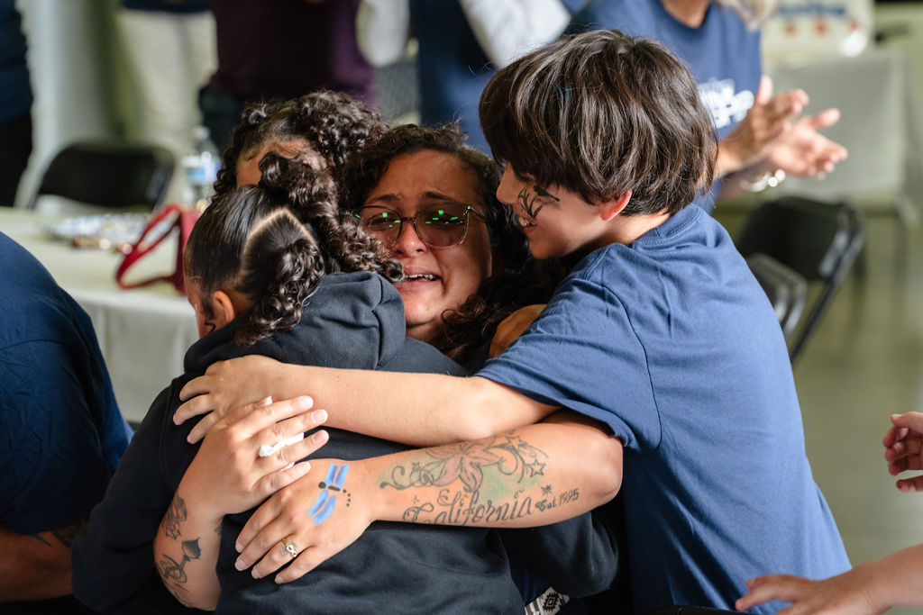 A tearful mother held by her children at the Tacoma charity car giveaway