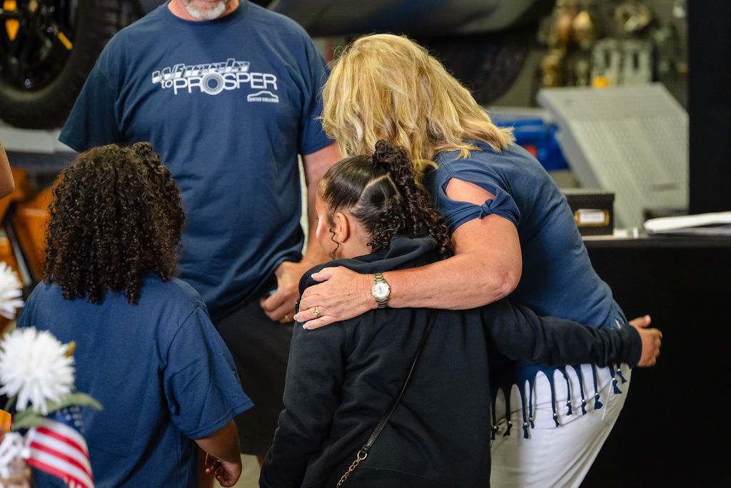 A volunteer holds two daughters close during the Tacoma charity car giveaway