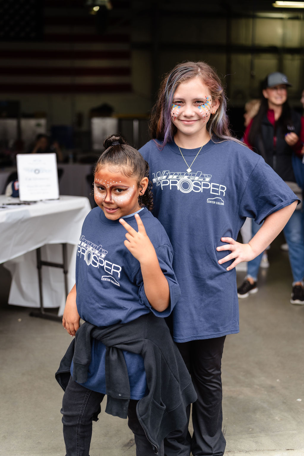 Two girls with painted faces wearing Wheels to Prosper shirts in Tacoma