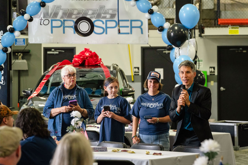 Volunteers in matching shirts stand near the donated car during a Tacoma charity giveaway