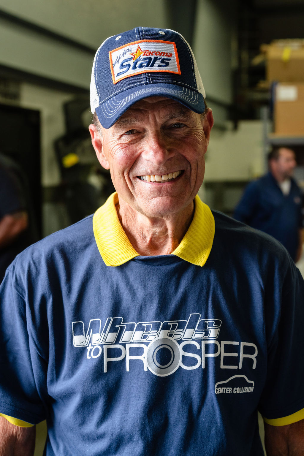 Portrait of a smiling volunteer wearing a Wheels to Prosper shirt and cap