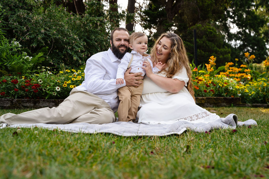 Parents snuggling their little boy on a blanket during golden hour family photos at Point Defiance Tacoma