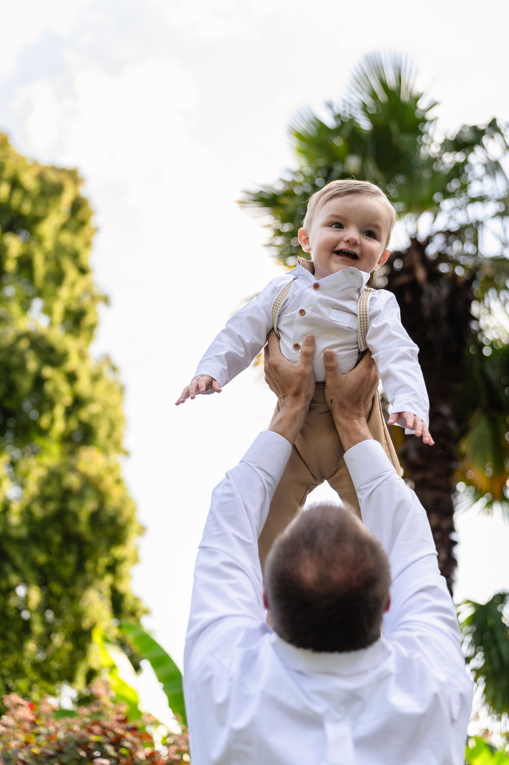 Little boy laughing as his dad lifts him skyward in the gardens at Point Defiance in Tacoma