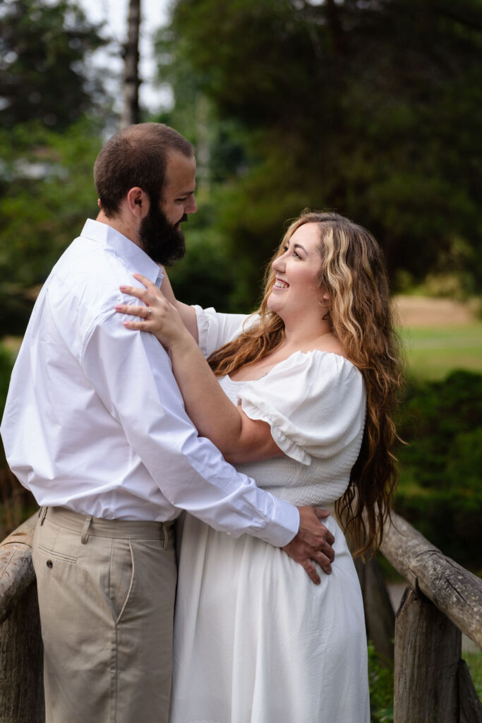 Engaged couple holding each other and laughing at the Point Defiance Rose Garden in Tacoma