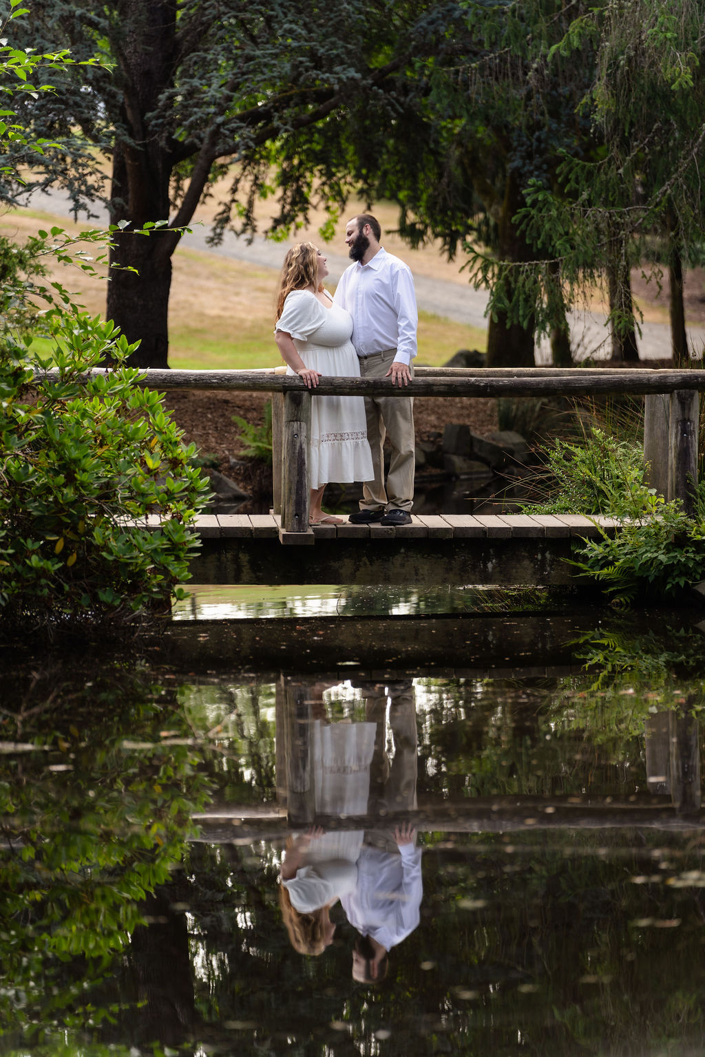 Engaged couple on the pond footbridge with their reflection at Point Defiance Park in Tacoma