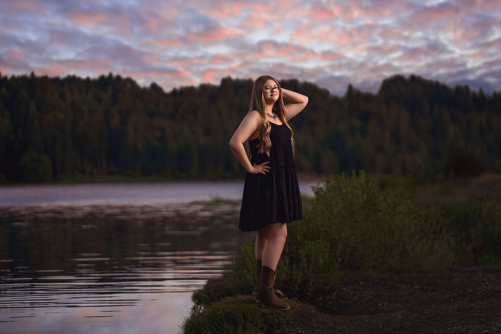 Senior girl at the water's edge under a vivid pink and purple sunset at Belfair State Park