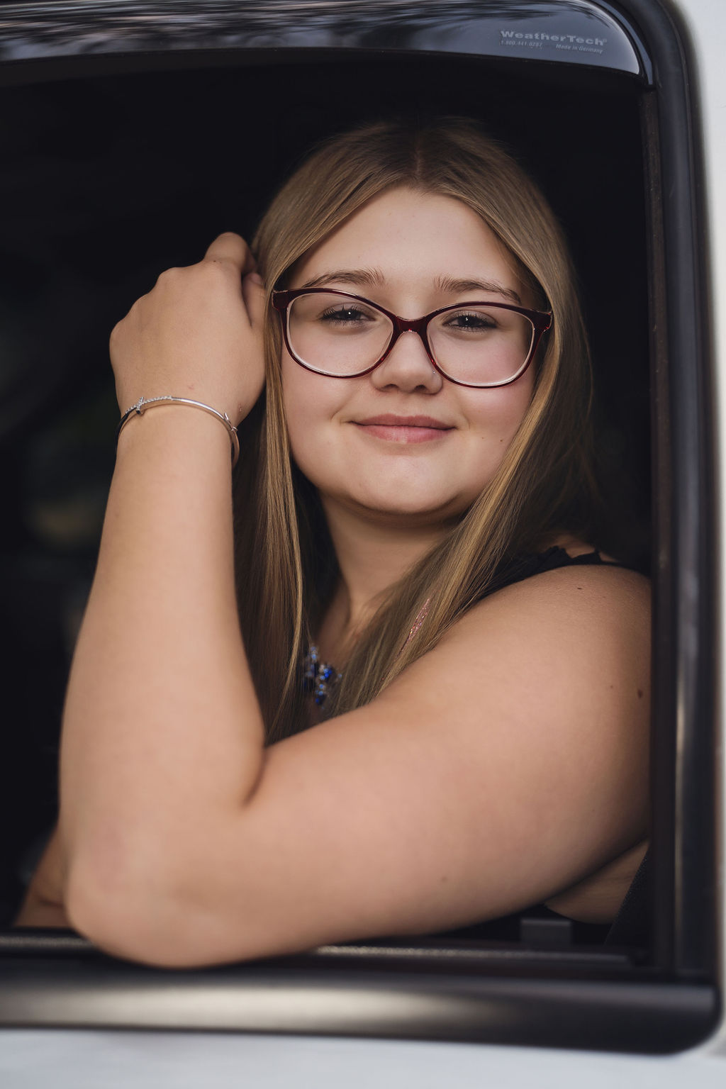 Senior leaning out a pickup truck window with her hand in her hair near Hood Canal in Belfair