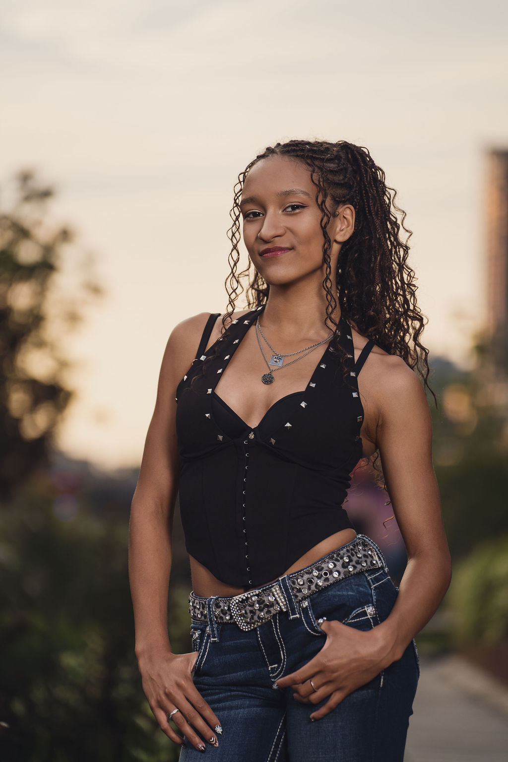 High school senior with thumbs in her jean pockets under a soft golden hour sky, a look every Bremerton senior photographer loves for city sessions