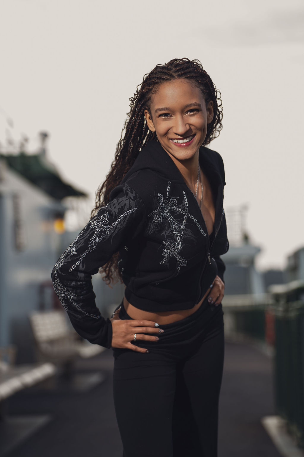 High school senior in a rhinestone hoodie smiling with both hands on her hips on the open ferry deck under a bright overcast sky during a Puget Sound crossing.