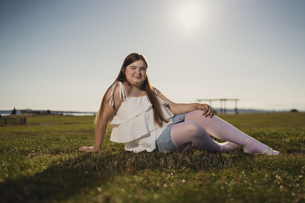 Senior seated on the grass leaning back in the golden light at Chambers Bay