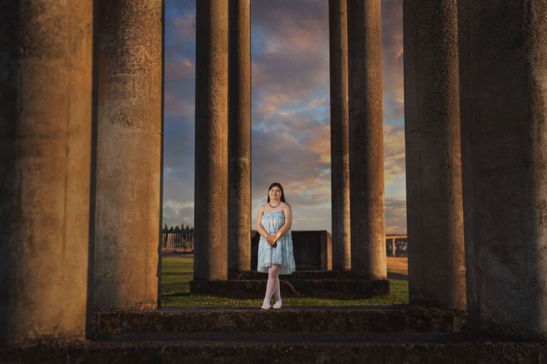 Senior framed by the columns with sunset clouds behind at Chambers Bay