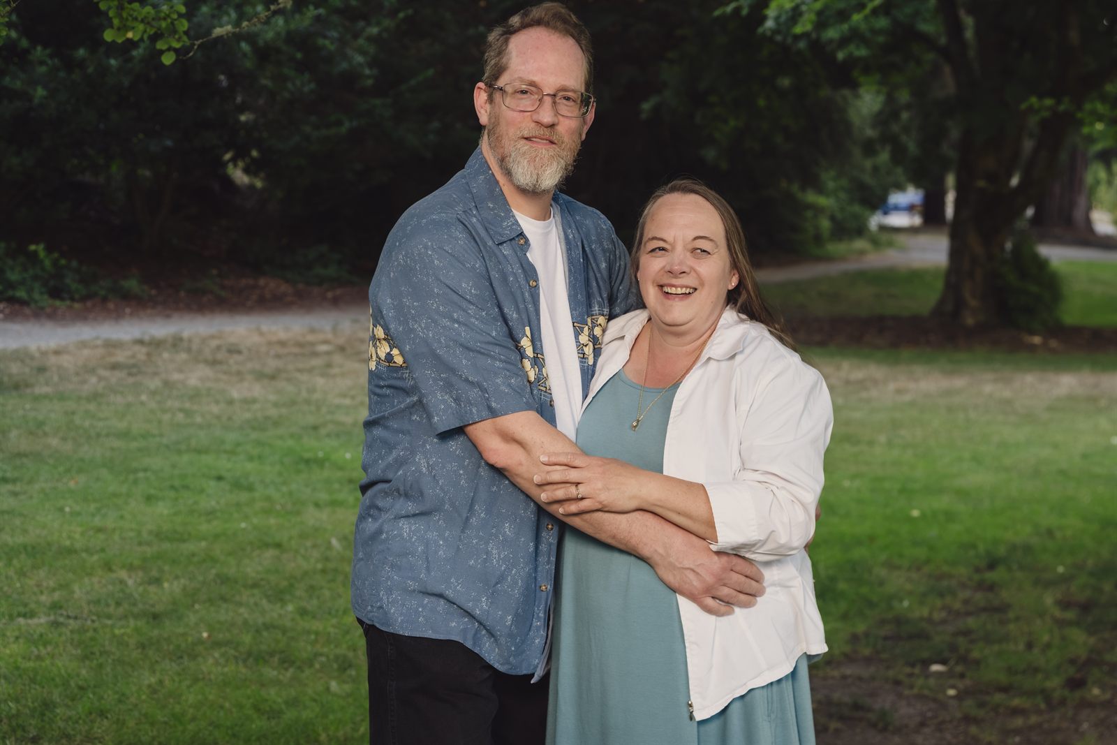 Parents laughing together at golden hour on the lawn at Point Defiance Park in Tacoma