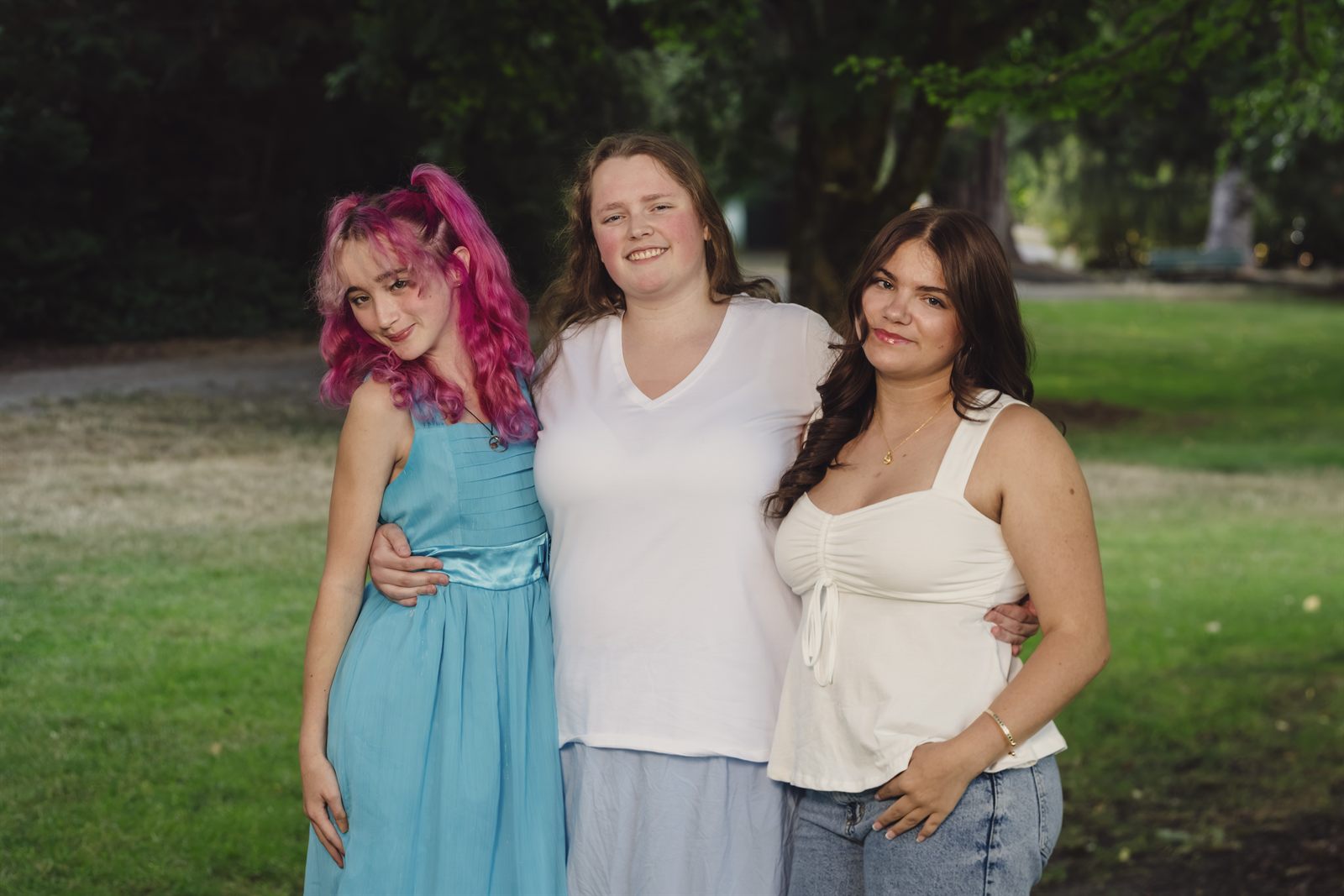 Three sisters posing together on the lawn at Point Defiance Park in Tacoma